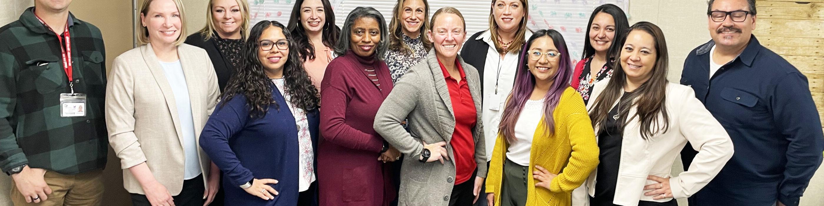 A group of teachers pose for a photography inside a classroom.